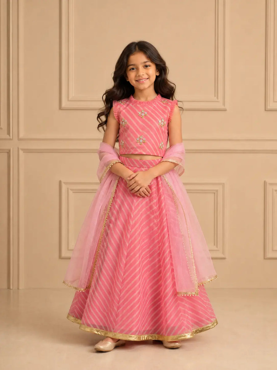 Baby pink lehenga set for girls worn by a smiling girl, showcasing Leheriya-inspired patterns for traditional occasions.
