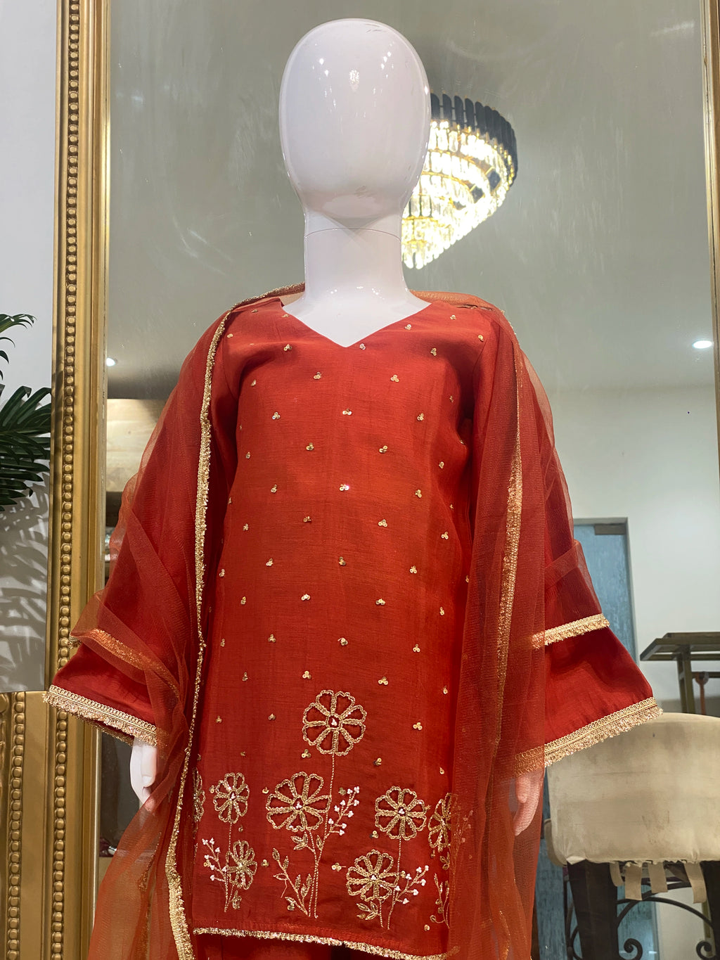Girl wearing red floral embroidered lehenga set with V-neck kurta, flared lehenga and sheer gold-border dupatta