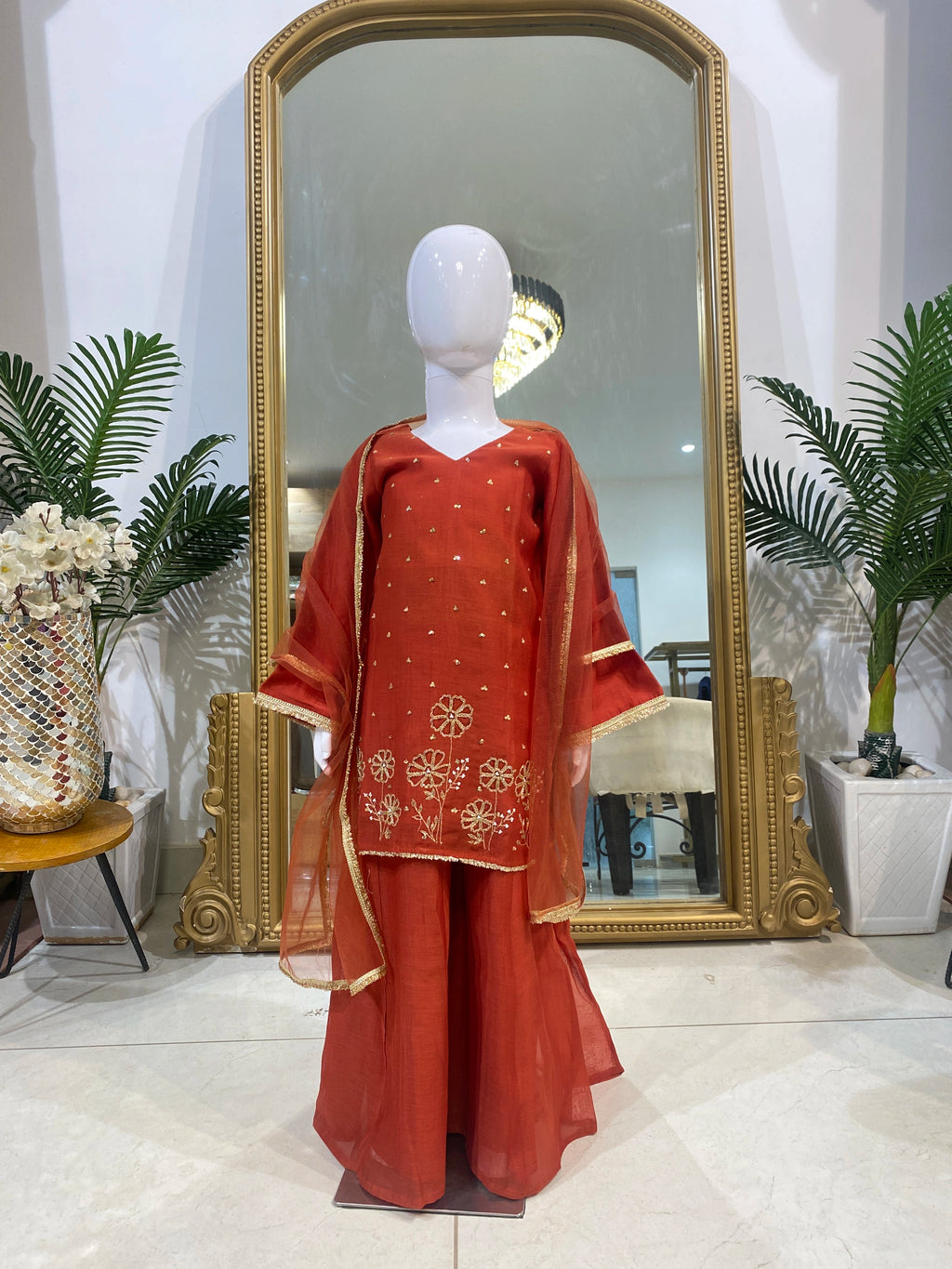 Girl wearing red floral embroidered lehenga set with V-neck kurta, flared lehenga and sheer gold-border dupatta
