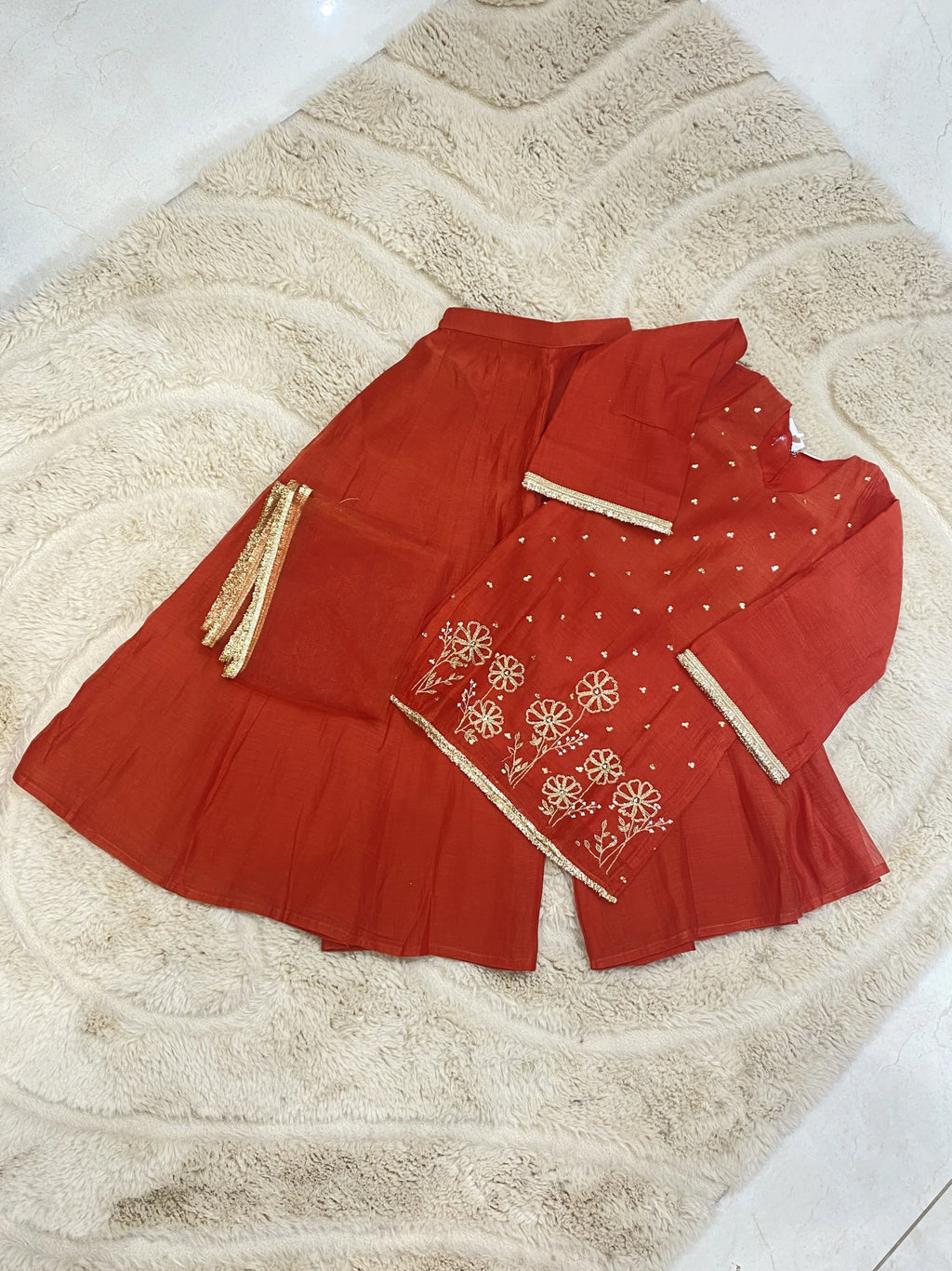 Girl wearing red floral embroidered lehenga set with V-neck kurta, flared lehenga and sheer gold-border dupatta