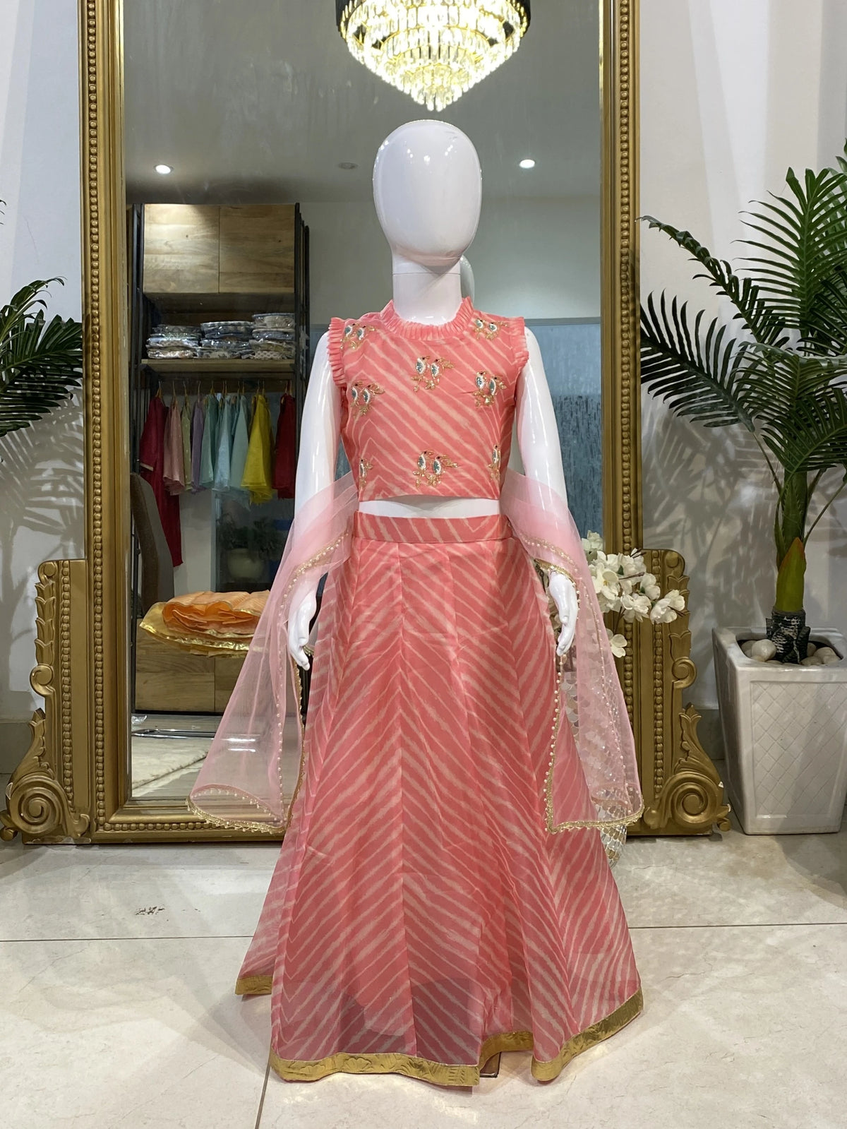 Light peach Leheriya lehenga set for girls with hand-embroidered bird motifs, ruffle choli, gold border and net dupatta