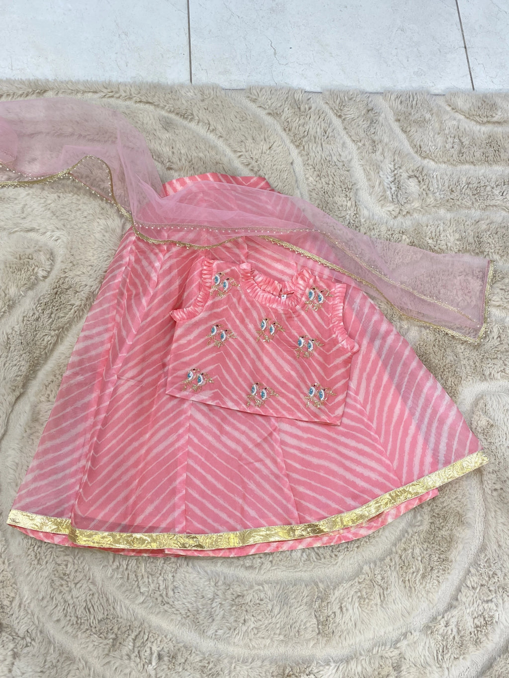 Light peach Leheriya lehenga set for girls with hand-embroidered bird motifs, ruffle choli, gold border and net dupatta