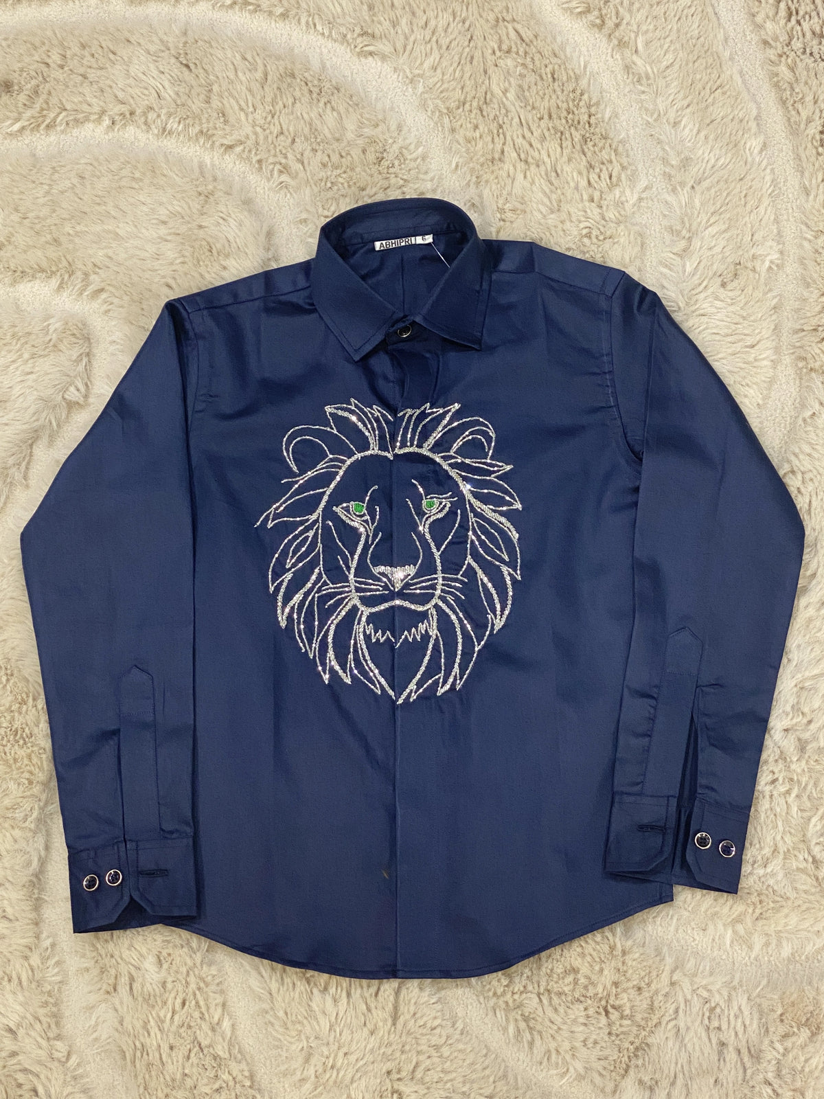 Lion embroidered shirt for boys featuring a large lion face motif and green eye accents on a navy blue background.